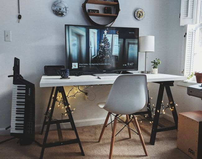 Espaço para home office com mesa, cadeira e tela grande de computador