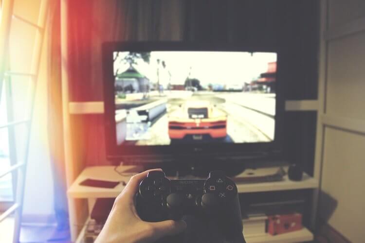 Mão segurando controle de video game em frente a tv